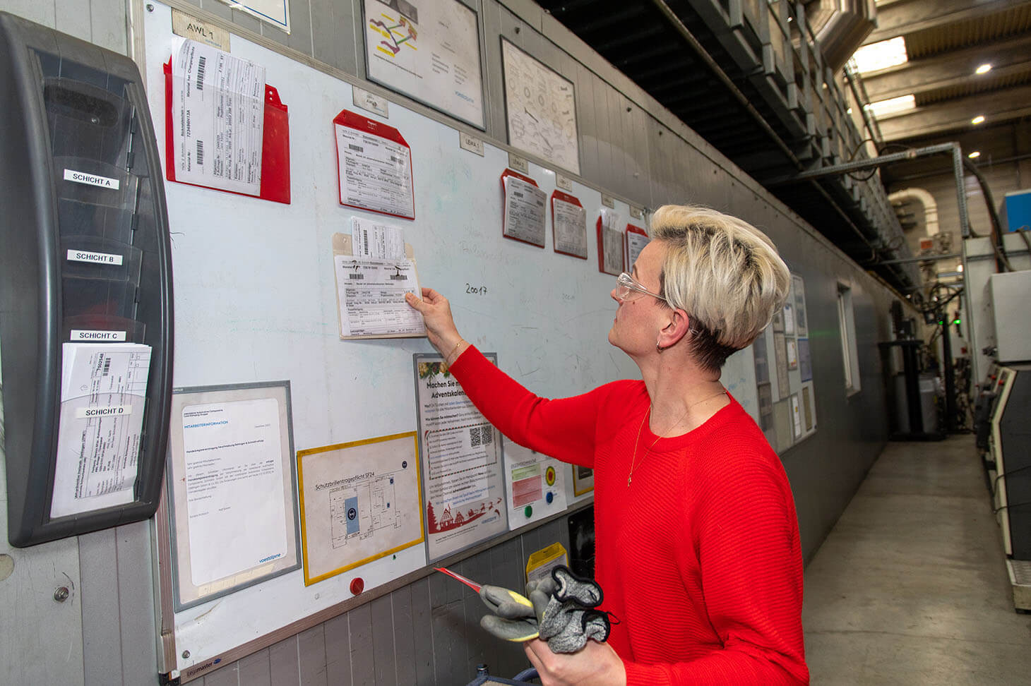 Fabienne Krause hängt eine Information auf die Wand, auf der Schichtpläne hängen