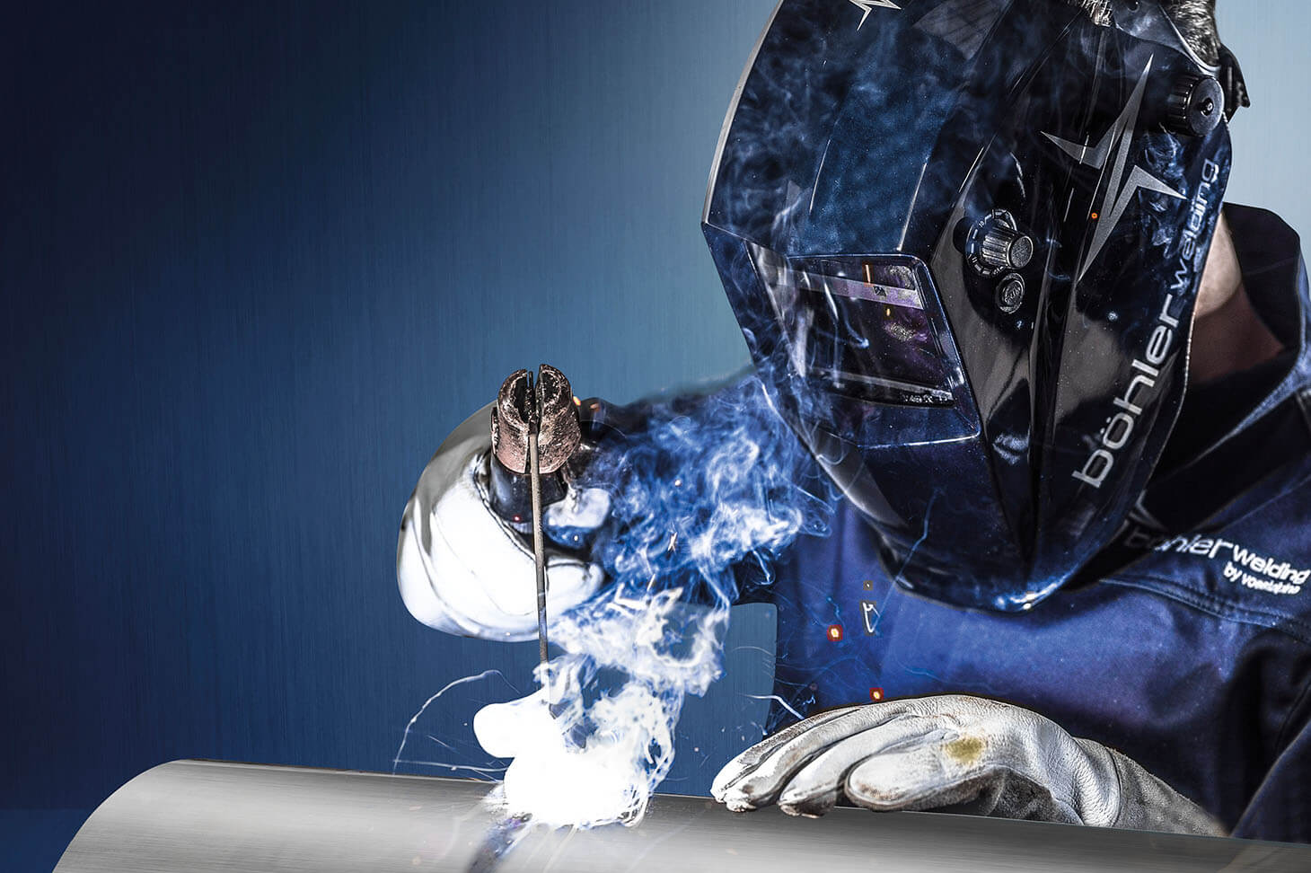 A Böhler Welding employee with head protection shield welds metal