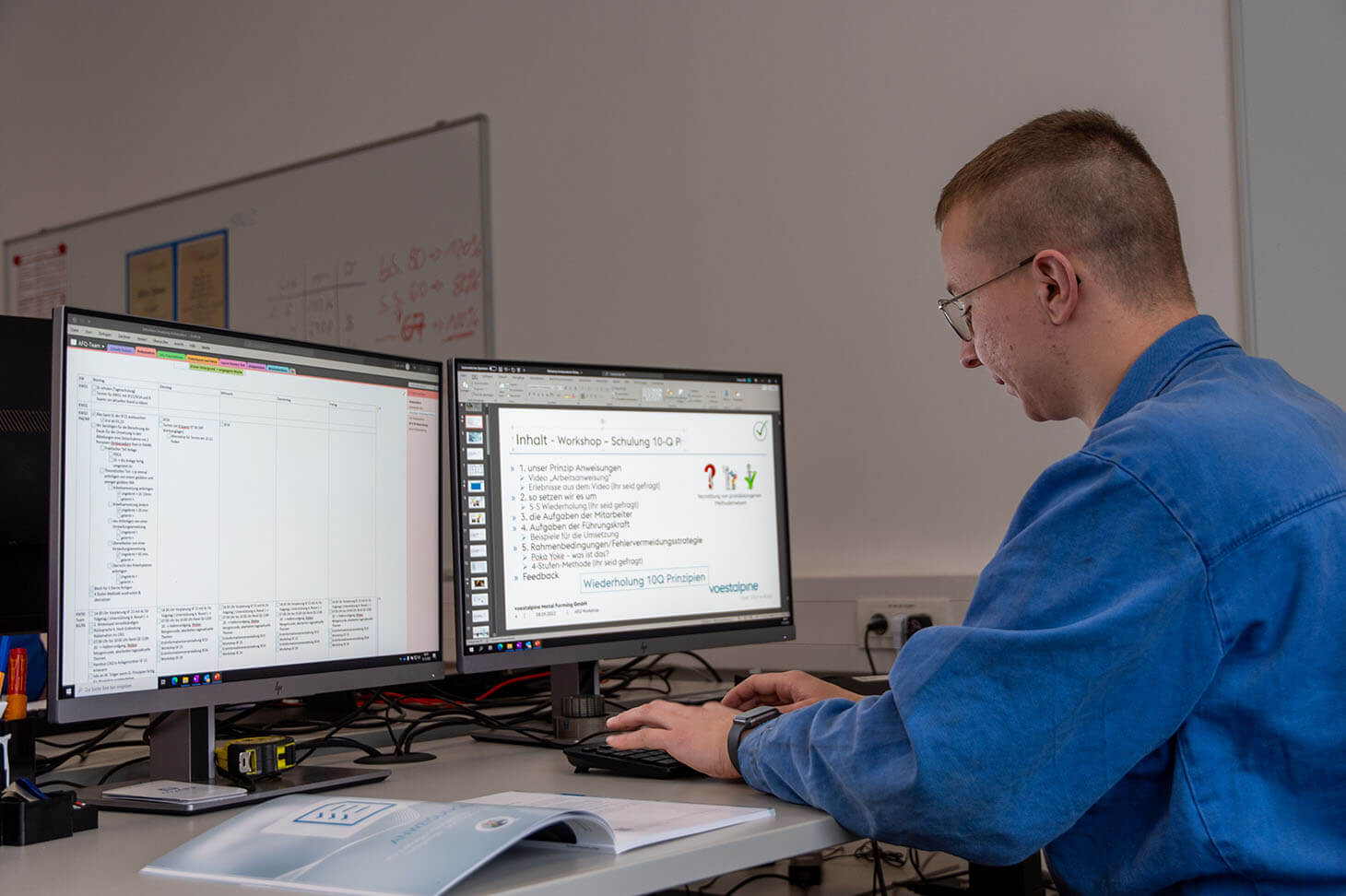 Dominik sits at a desk with 2 screens and prepares a presentation