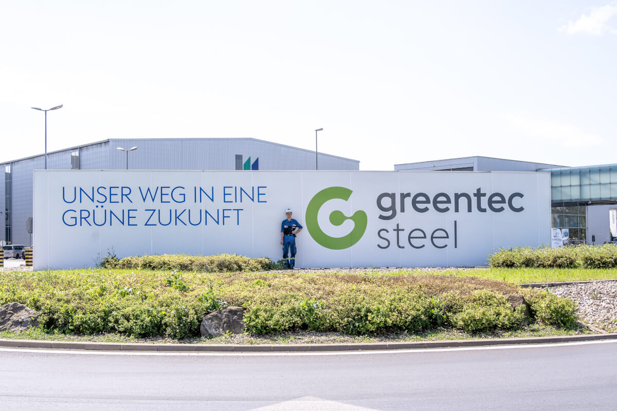 Sign "Our path to a green future", greentec steel, an employee poses in front of it