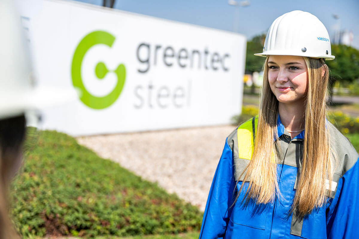 Junge Voestalpine Mitarbeiterin vor der greentec steel Tafel in Donawitz