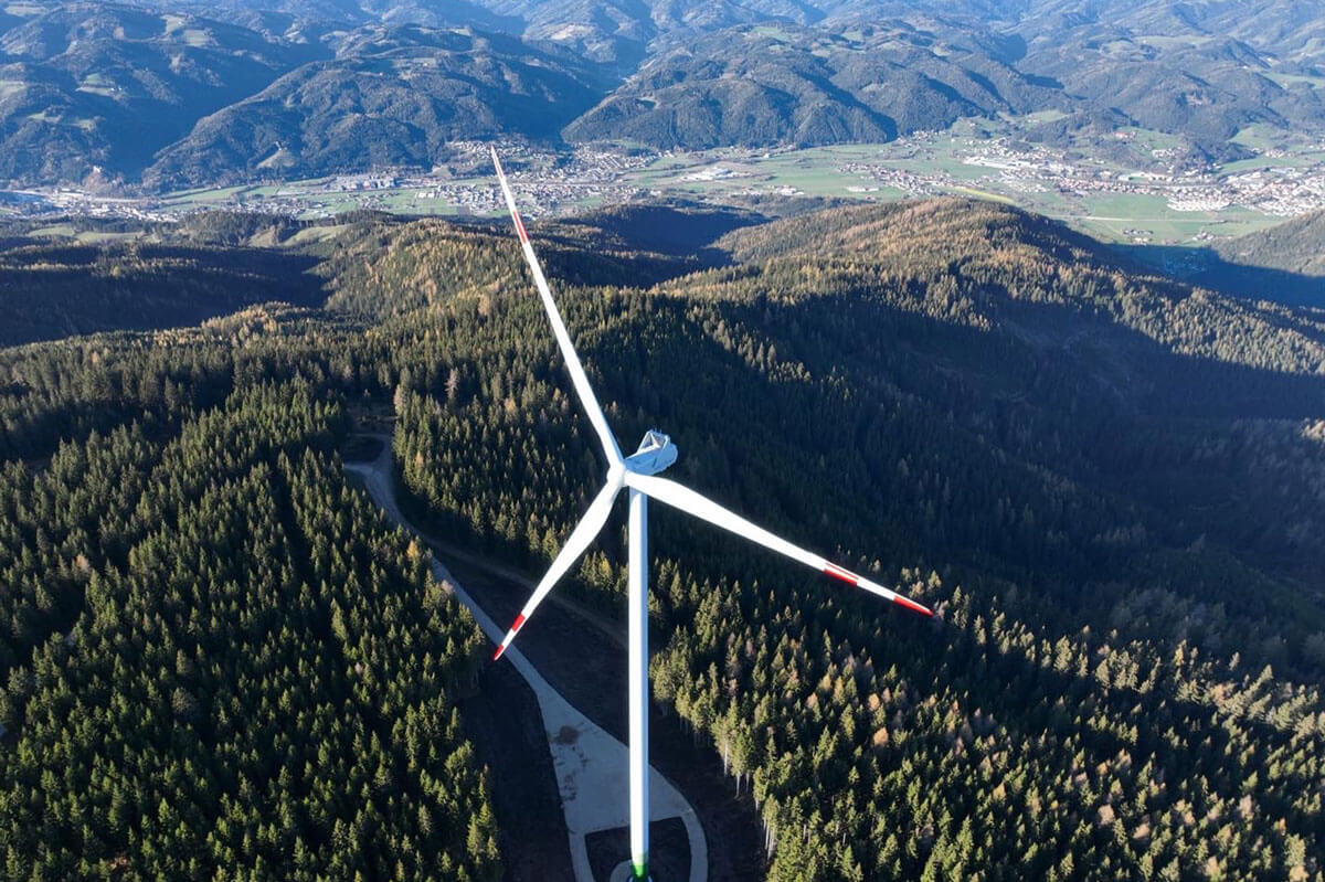 Luftaufnahme Windrad in der Mitte eines bewaldeten Hügels