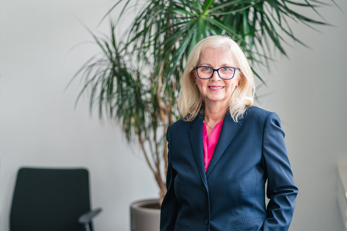 Portrait photo of Susanne Gutbrod in front of an indoor palm tree