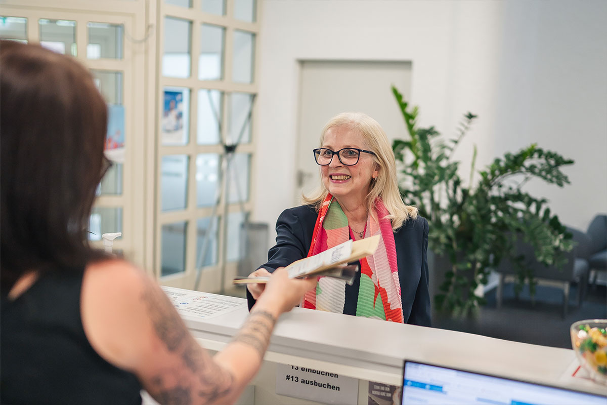 Susanne Gutbrod smiles as she accepts documents from a colleague