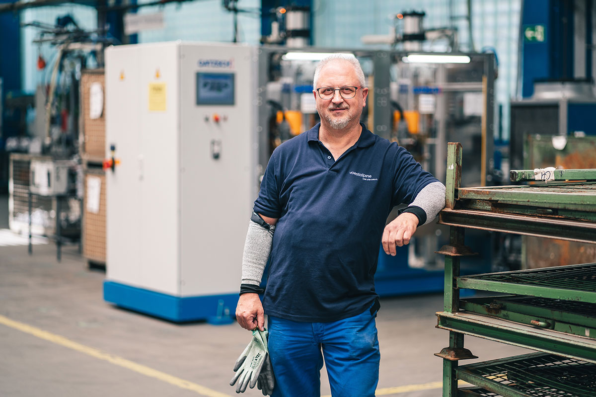 Bernd im Portrait in der Werkshalle an eine Metall Ablage gelehnt