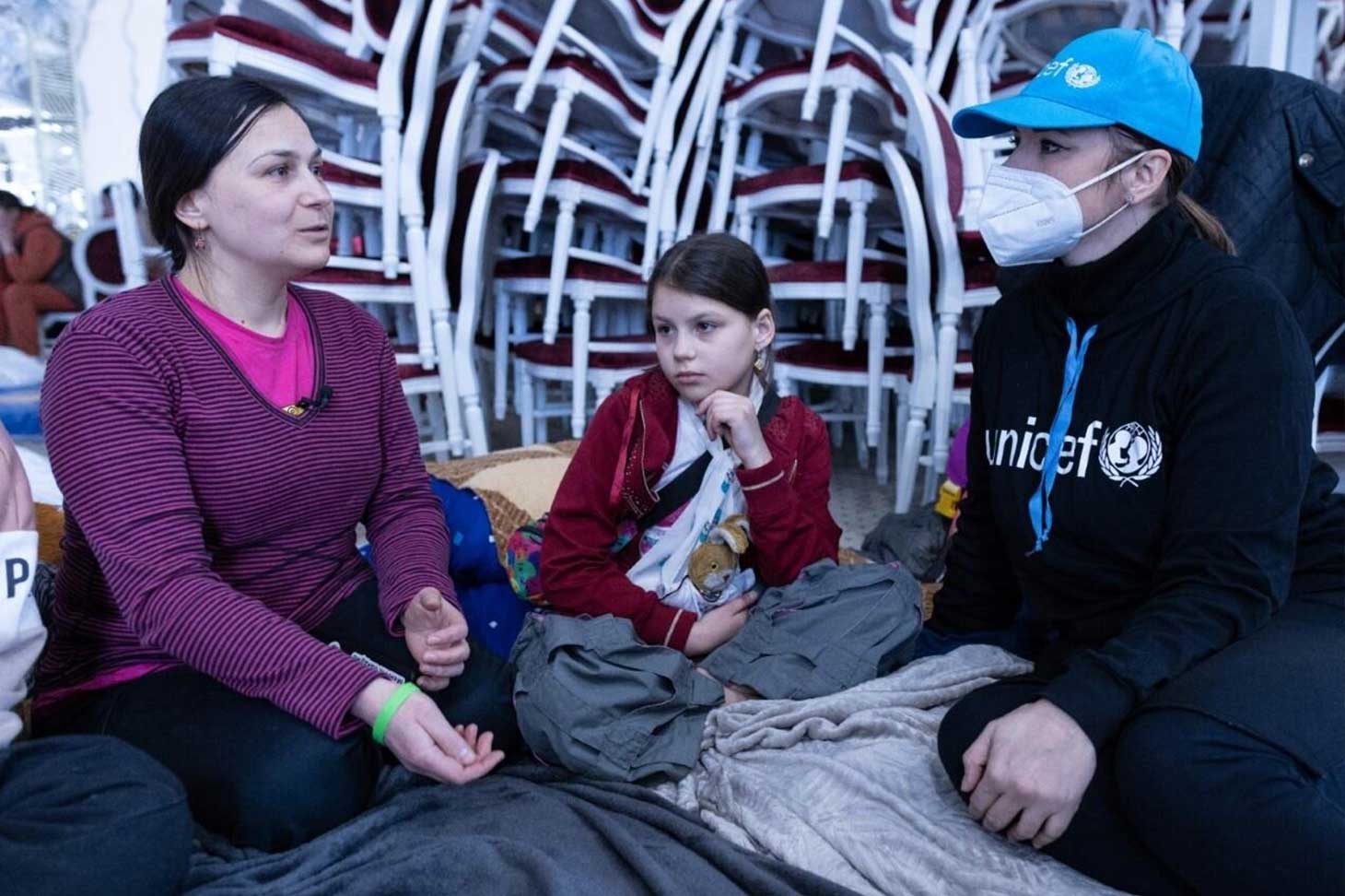 Two women and a girl sit on the floor in a Blue Dot family center supported by voestalpine