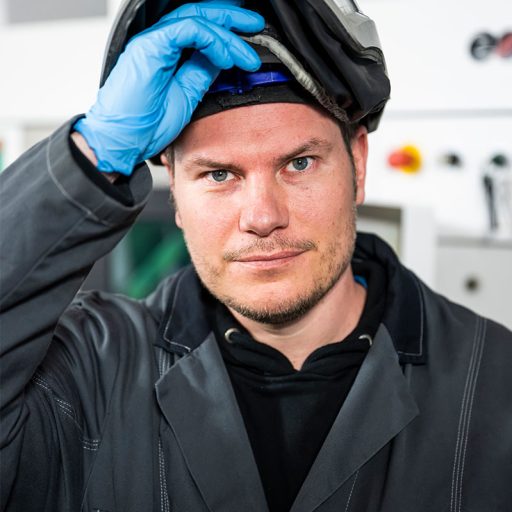 Portrait photo of Bastian, he opens the visor of his hard hat