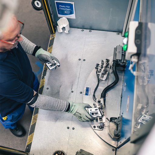 Bernd legt kleine Stahl Bauteile in eine Fertigungsmaschine