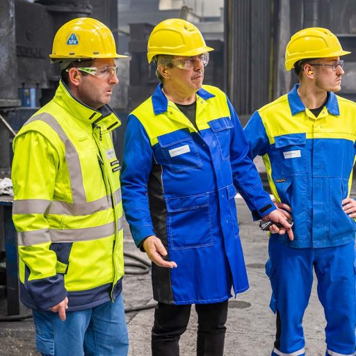 Lothar, Thomas und Sebastian mit Schutzkleidung, Schutzbrille und Helm, blicken rechts aus dem Bild