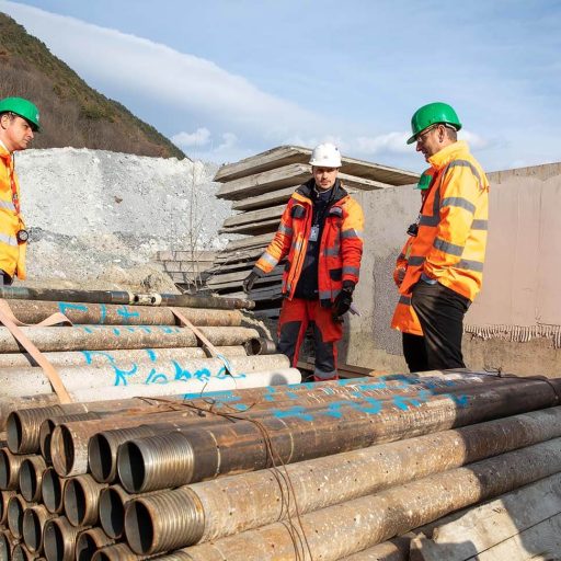 gestapelte voestalpine Tubulars-Vortriebsrohre und drei Mitarbeiter