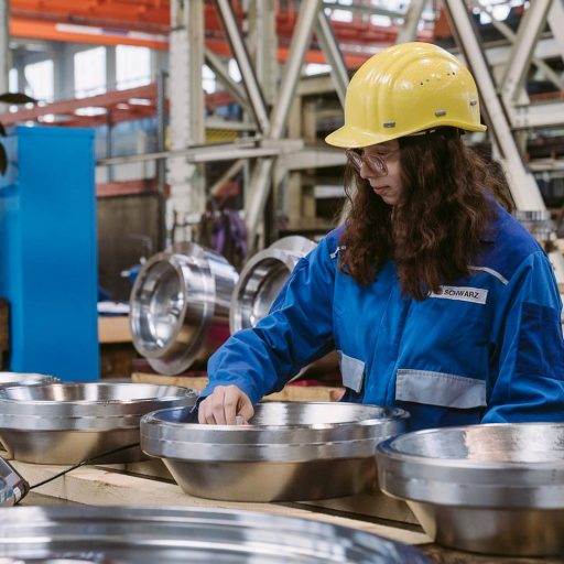 Ferialpraktikantin führt eine Messung an Stahlteilen im voestalpine Werk durch