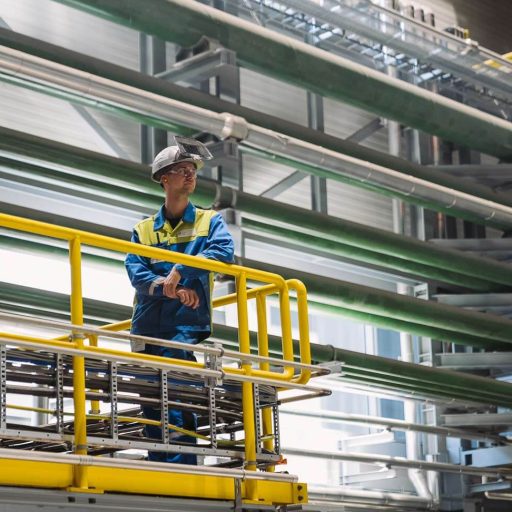 Employees in protective clothing leaning against a railing in the new stainless steel plant