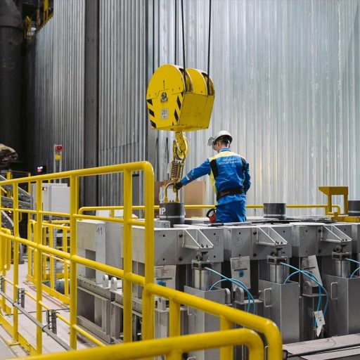 Employees in protective clothing working on a crane hook in the new stainless steel plant