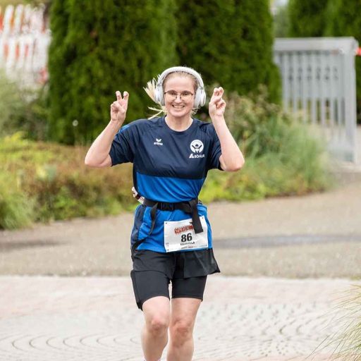 Läuferin währen des Laufes zeigt das Victory Symbol