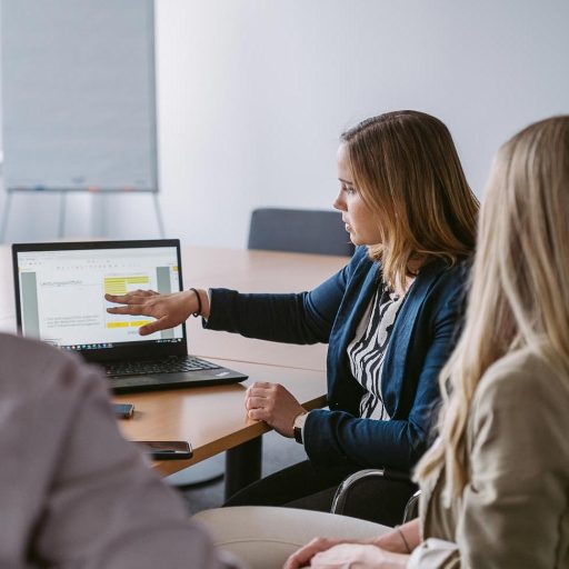 Katharina zeigt in einem Meeting auf Information auf Ihrem Laptop